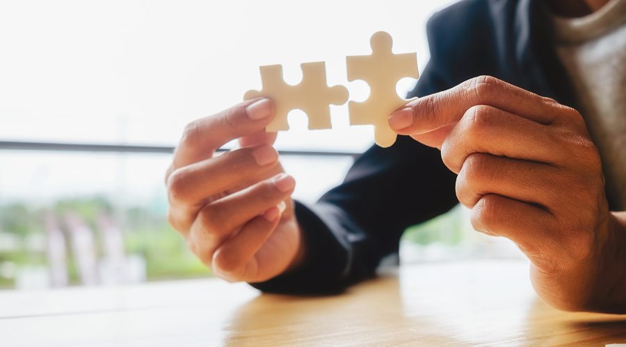 Business woman hands connecting jigsaw puzzle. Business solutions, success and strategy concept. Businessman hand connecting jigsaw puzzle.Close up photo with selective focus.