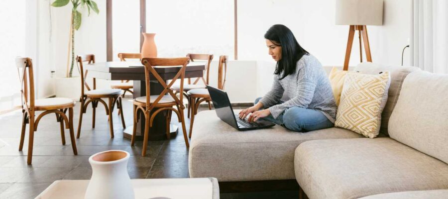 mujer sentada en un sofá con una laptop